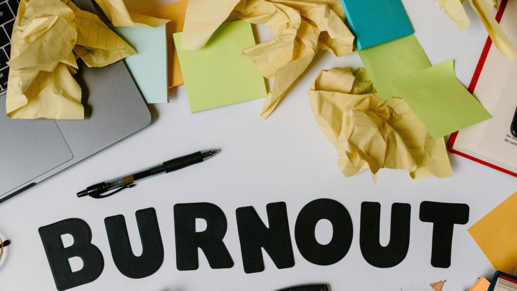 Symbolic image of burnout with crumpled papers and office supplies on a cluttered workspace.