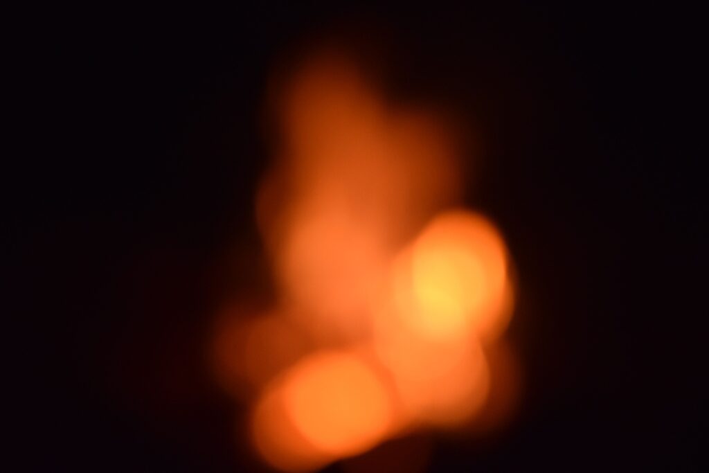 Blurred orange and yellow bokeh lights on a dark background, creating a warm abstract effect.