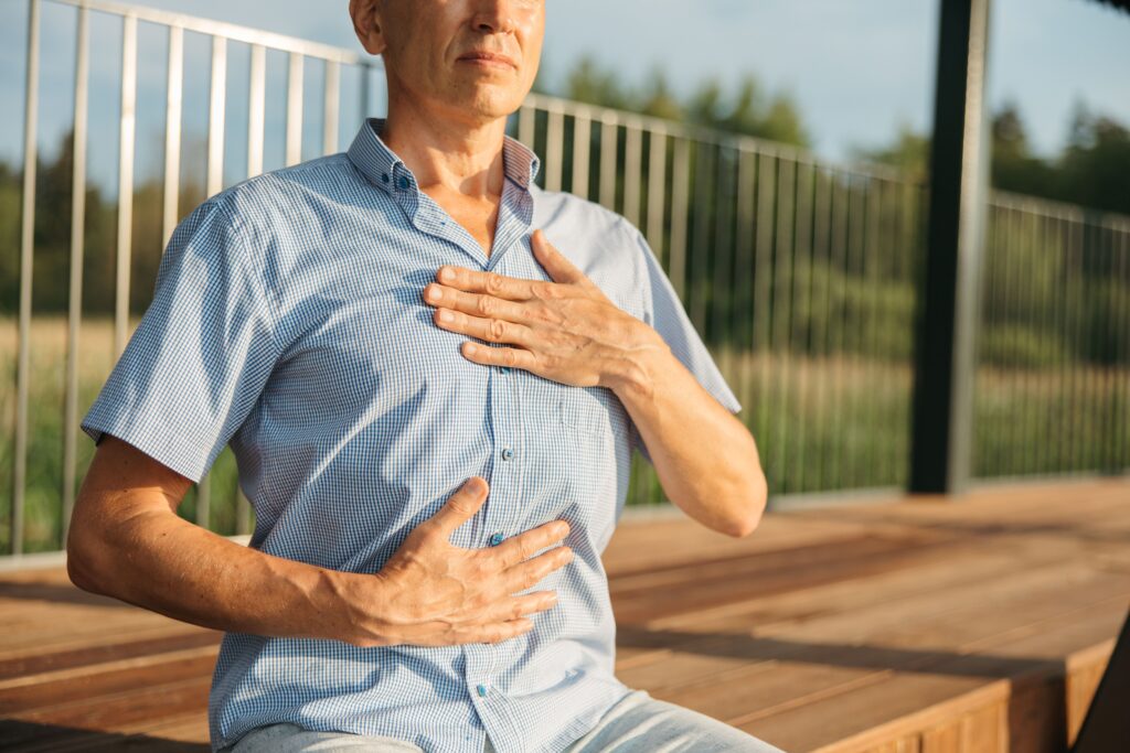 A man practicing relaxation with hands on chest and abdomen outdoors. Sophrologie et hypnose